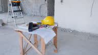 istock Construction site with yellow hardhat, work tools, architectural plan on the table and ladder 1645803735