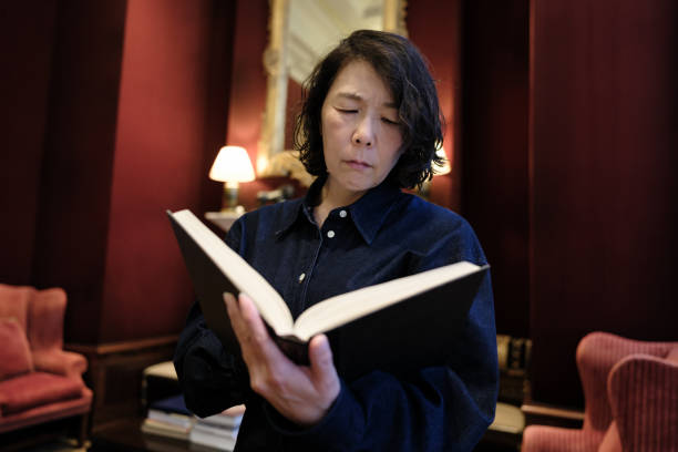 istock Asian woman reading a book at home 1645814408