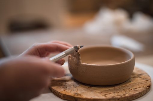 girl hands, pottery studio and painting cup in workshop for makes a creative mug in the form of a frog. Painter, ceramics product and brush process, artistic pattern or production in small business