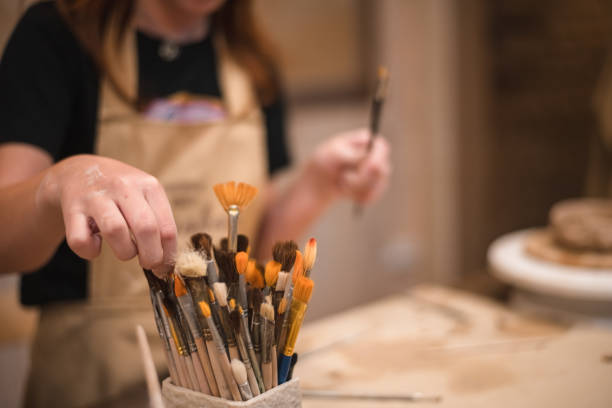 istock A girl in a creative workshop holds brushes for coloring a clay product 1645829307