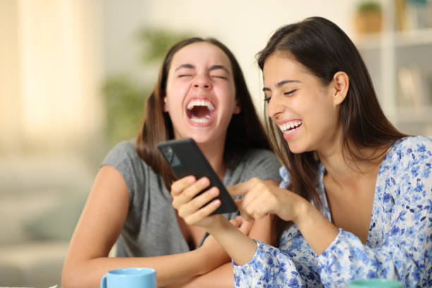 istock Two happy friends laughing hilarious using phone at home 1645832004