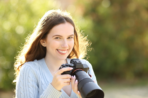 Photographer posing in a park holding mirrorless