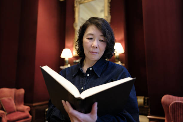 istock Smiling woman reading a book at home 1645843004