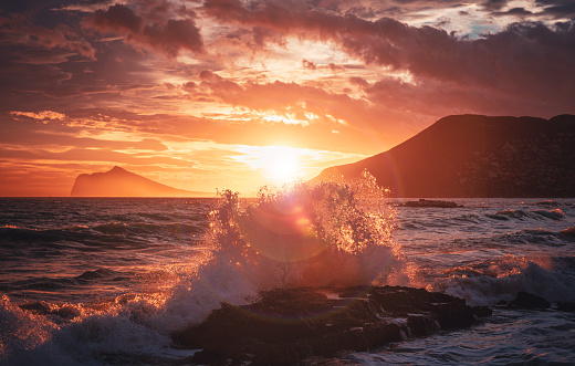 Splashing wave, mountain and sunset