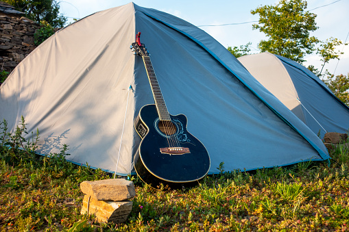 Uttarakhand campsite: Dome tents, acoustic guitar amidst nature's embrace. Perfect camping retreat.