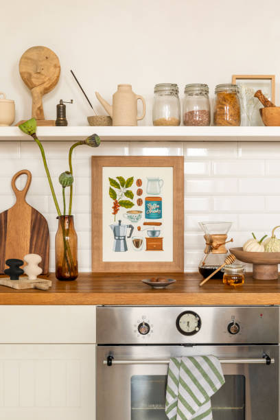 Cozy composition of kitchen interior with mock up poster frame, vase with flowers, white tile, wooden countertop, jar with spices, silver oven, vegetable and personal accessories. Home decor. Template composición acogedora del interior de la cocina con marco de póster de maqueta, jarrón con flores, azulejos blancos, encimera de madera, tarro con especias, horno de plata, verduras y accesorios personales. decoración del hogar. plantilla