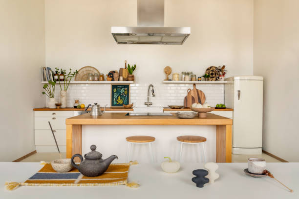 istock Warm and cozy kitchen interior with mock up poster frame, wooden kitchen island, barstool, fridge, white kitchen furniture, gray pitcher, salt cellar and kitchen accessories. Home decor. Template. 1645859521
