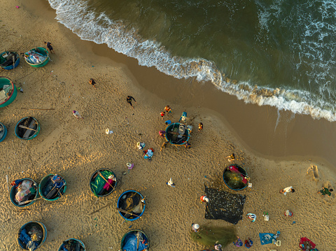Drone view of a fish market on Mui Ne beach in early morning with full of fishes on the basket boat, Mui Ne beach, Phan Thiet, Binh Thuan province, central Vietnam