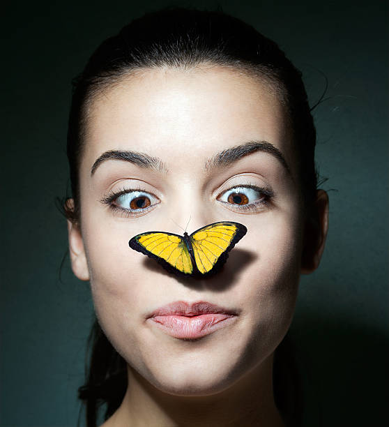 überrascht mädchen mit einem schmetterling auf ihre nase - butterfly women humor fun stock-fotos und bilder