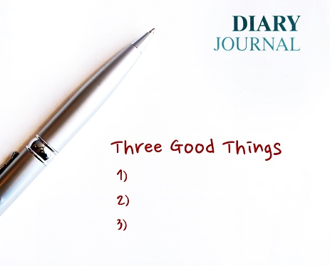Pen on diary journal book with handwritten text Three good things - gratitude practice journal to track daily reflections, find three good things to be grateful for