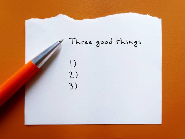 Pen on orange background with handwritten text Three good things - gratitude practice journal to track daily reflections, find three good things to be grateful for
