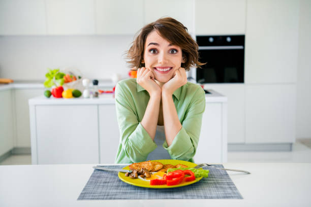 屋内の家の台所でおいしい夕食を食べるのを待っている興奮したファンキーな女性の緑のシャツの写真 - stereotypical housewife women domestic kitchen brown hair ストックフォトと画像