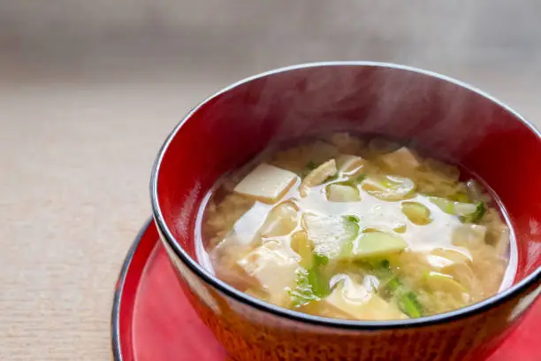 Miso soup with radish and tofu in a red bowl
