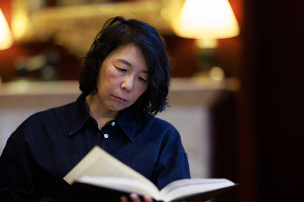 istock Asian woman reading a book at home 1645930986