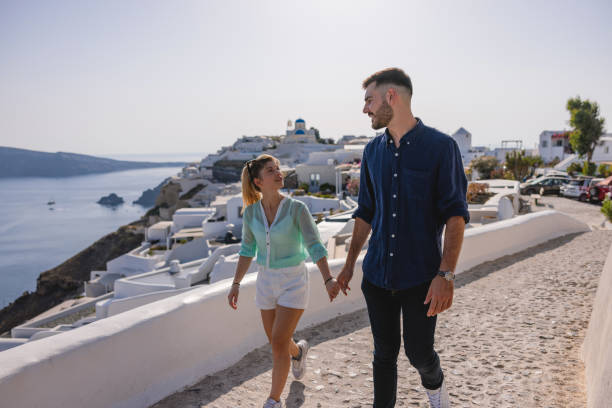 istock Charming Young Couple Holding Hands While Exploring Village Of Oia 1645938304