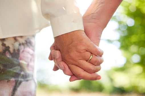 Love, holding hands and marriage, old couple in nature together for support and trust in healthy commitment. Retirement, hand of senior woman and elderly man in garden for partnership or relationship