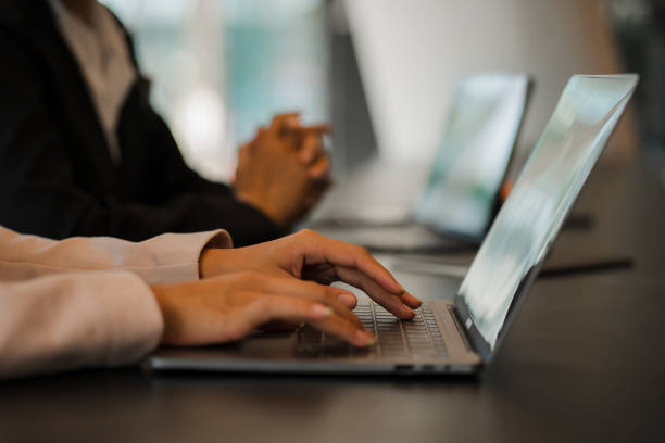 istock Side view of business woman's hands using laptop computer resting, young woman writing in blank notebook placed on office table with laptop keyboard close up pictures 1645944396