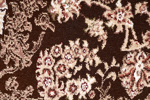 Textured fragment of contrast persian carpet, macro photo for background. Close up view of details of pattern with floral ornament of short pile rug. Concept of texture and background.