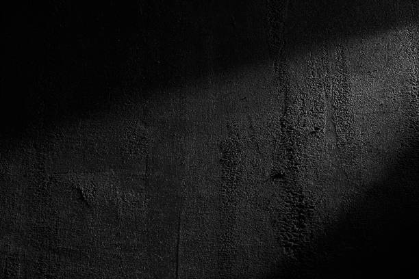 Black wall rough texture background, concrete floor or old grunge backdrop. Black wall rough texture background, concrete floor or old grunge backdrop, illuminated by sun ray. Close up of dark graphite surface for modern background design. Concept of textures and background. light concrete texture stock pictures, royalty-free photos & images