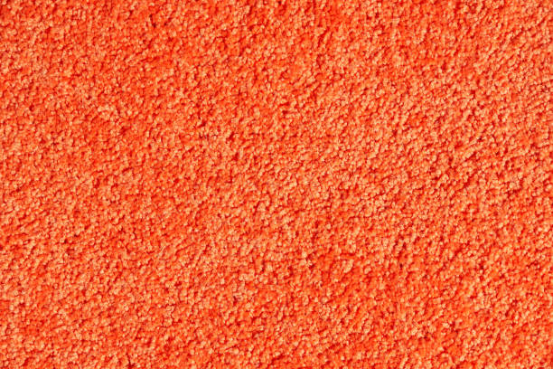 Orange saturated, soft fleece carpet texture background. Close up of artificial wool fabric texture fragment shaggy rug. Concept of textures and backgrounds.