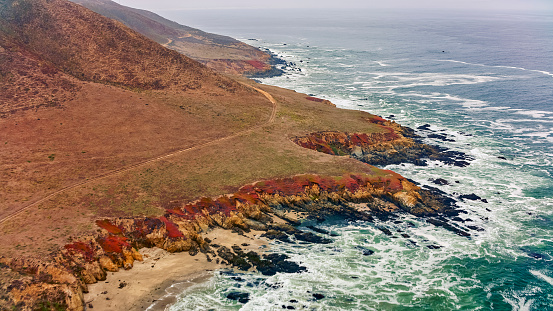 Aerial view of waves splashing along rocky coastline, California, USA.