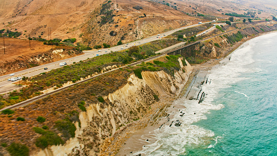Aerial view of vehicles driving on highway by sea, California, USA.