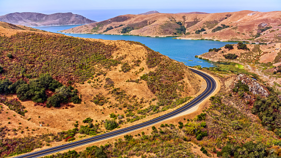 Aerial view of road passing by hills with lake in background, California, USA.