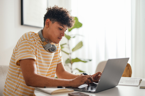 istock Portrait of a Handsome Teenage Boy Sitting at the Desk and Using a Laptop Computer in His Room at Home 1645960635