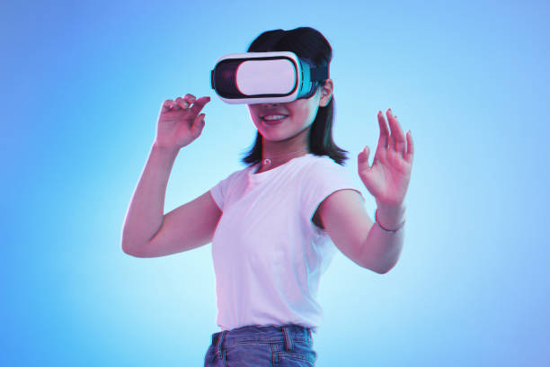 istock Metaverse gaming, headset and woman on blue background for virtual reality creativity. Smile, touching and a girl with digital glasses for a cyber game, experience or future technology on a backdrop 1645970453