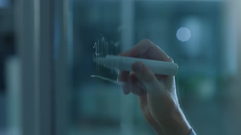 Person, hands and writing on glass board in schedule planning, brainstorming or tasks at the office. Closeup of employee in project plan, agenda or reminder for company goals or mission at workplace