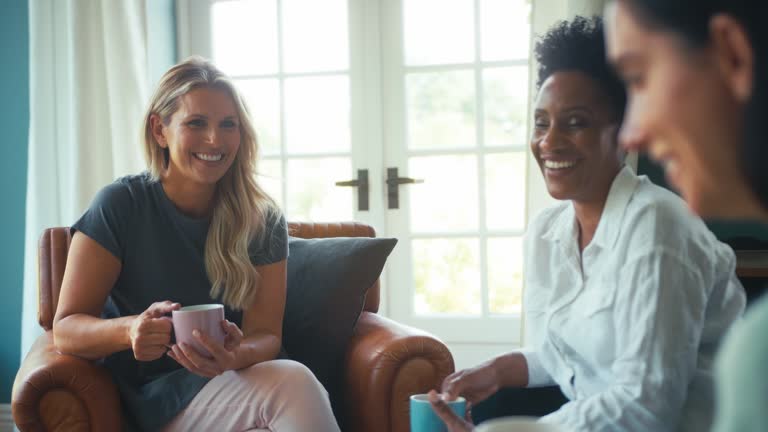 Three Mature Female Friends In Lounge At Home Meeting For A Chat And Hot Drink