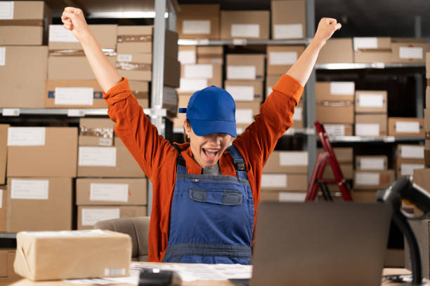 istock Storage worker celebrating victory and success sitting in warehouse before laptop computer. 1646034397