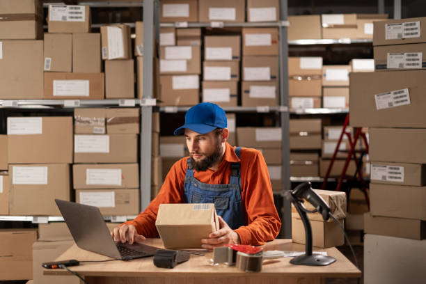 istock Inventory male worker to check order number on a parcel, using laptop computer, preparing a cardboard Box for postage and delivery. Working day in warehouse 1646034420