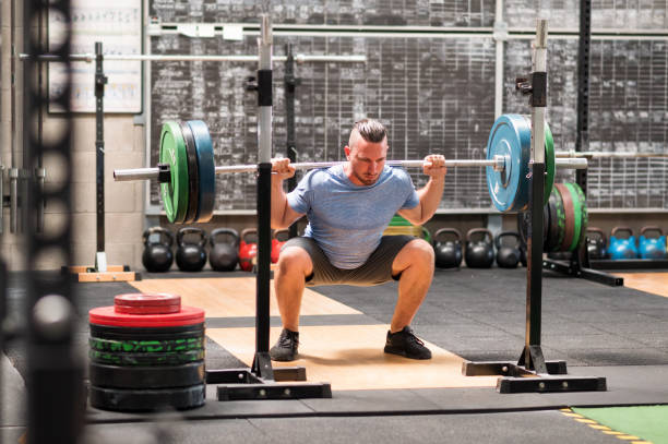 istock Sportsman doing back squat exercise with barbell in gym 1646048918