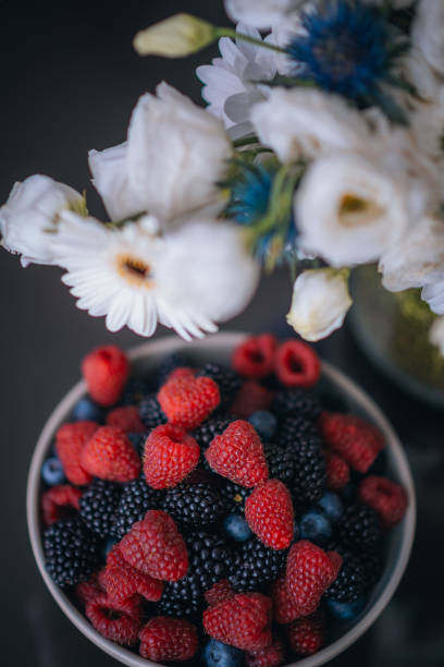 nahaufnahme eines tellers mit köstlichen, frischen beeren und einem blumenstrauß. - comfort food high angle view directly above close up stock-fotos und bilder