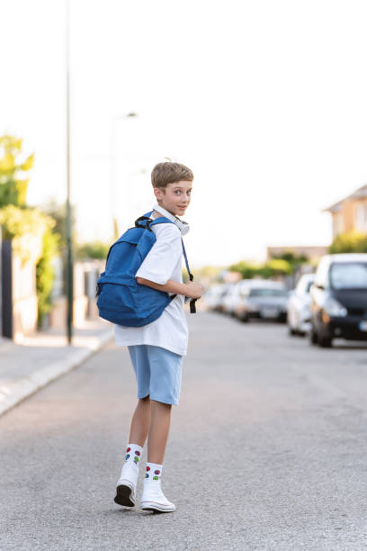 istock Young student boy with backpack looking at the camera while walking on the street. 1646090810