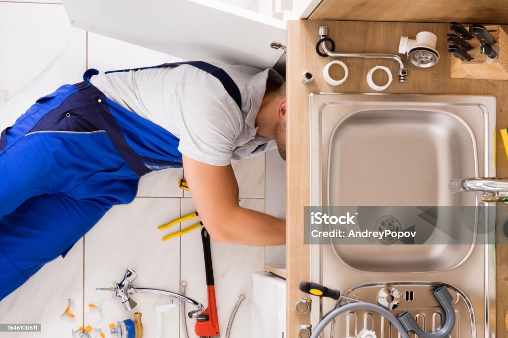 Male Plumber In Overall Fixing Sink Pipe High Angle View Of Male Plumber In Overall Fixing Sink Pipe Sink Stock Photo