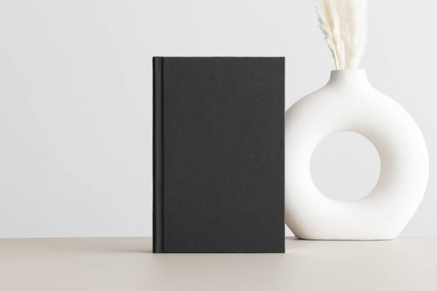 istock Black book mockup with a pampas decoration on the beige table. 1646109364