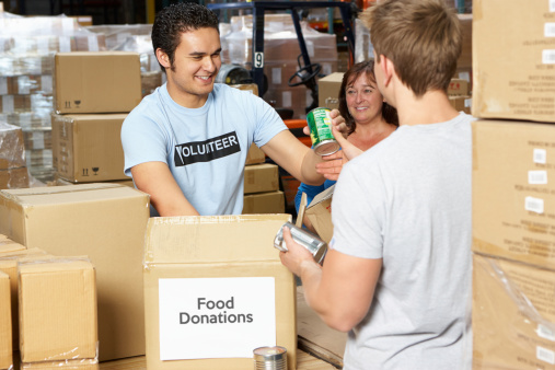 Volunteers Collecting Food Donations In Warehouse Smiling