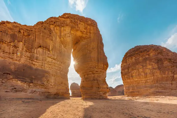 Jabal AlFil - Elephant Rock in Al Ula desert landscape, bright sun creates sunrays behind.