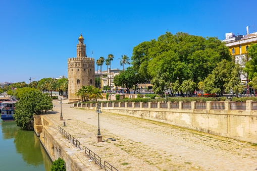 Seville, Spain - July 28, 2023. Paseo Alcalde Marques del Contadero promenade with the Torre del Oro tower in the background. Seville, Andalusia, Spain.