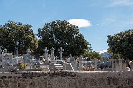 Small Catholic cemetery where you can see niches, tombs and crosses built mostly in gray granite stone, On a day of clear blue skies