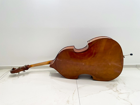 cello lying on a white marble floor with black veins, from the back against a white background