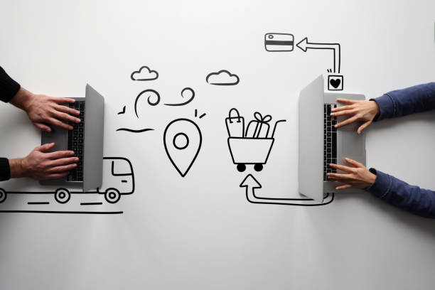The concept of online shopping and delivery. Two people using computers and drawings of shopping trolley, credit card and cargo lorry on the table drop shipping stock pictures, royalty-free photos & images