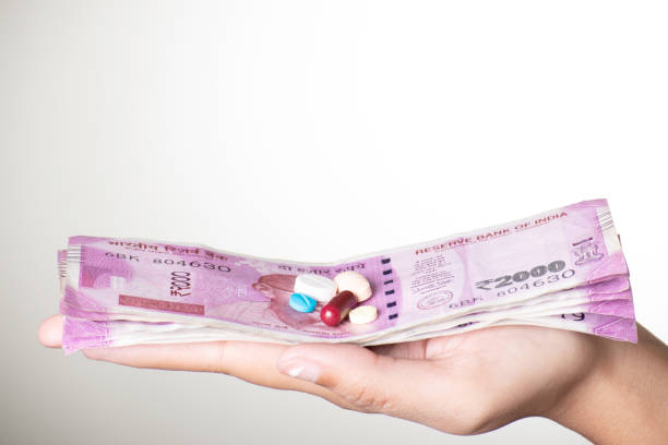 Indian currency note and medicine in hand on grey background