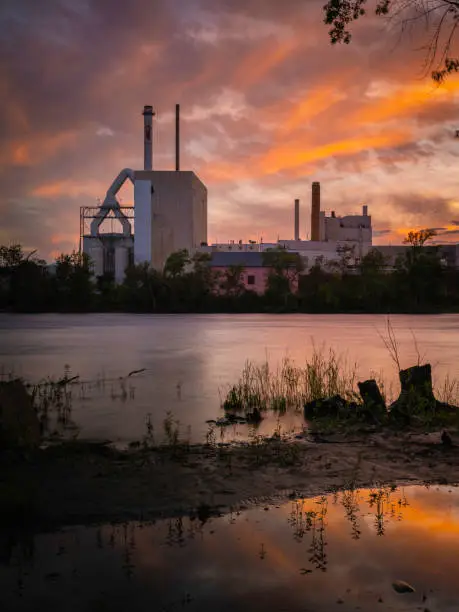 Photo of Sunset over Penobscot River in Bradley, north of Bangor, Maine, with the views of old factories in silhouette