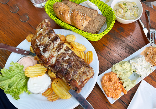 traditional Austrian dish of pork ribs with potatoes with an assortment of cheese spreads on a wooden table in a wine restaurant