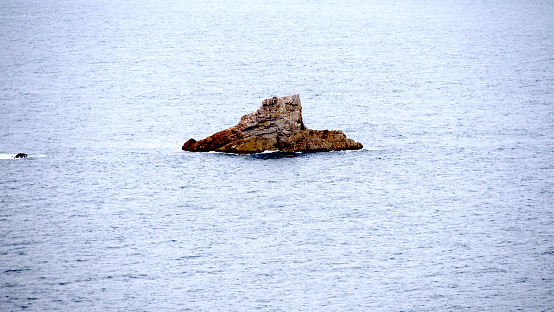 rock in the middle of the sea beaten by waves