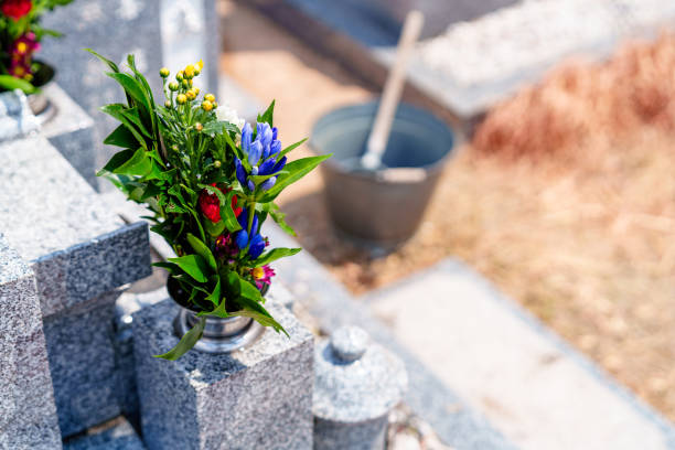 A woman cleans the grave. Sweeps leaves from the tombstone. Preparations for All Saints Day on November 1