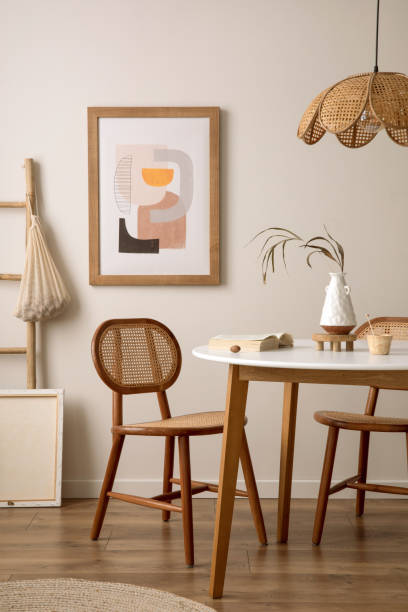 istock Creative composition of dining room interior with round table, rattan chair, wooden commode, pock up poster and kitchen accessories. Beige wall with mock up poster. Home decor. Template. 1646219874